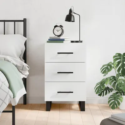 A white bedside table with three drawers is shown in a bedroom setting next to a bed.