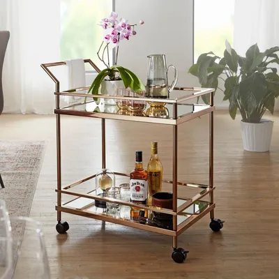 A bar cart with drinks and decorations in a living room setting.