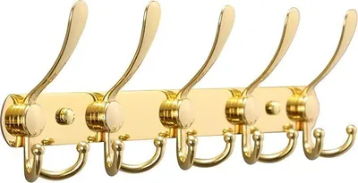 A gold colored coat rack with five hooks, mounted on a light yellow rectangular plate.