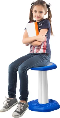 A young girl is sitting on a stool, holding a book.