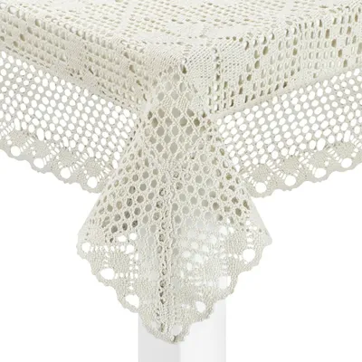 A close-up view of a crocheted tablecloth draped over a table corner.