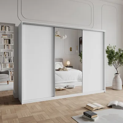 A bedroom scene with a large white wardrobe with mirrored doors, a bed reflected in the mirror, and a bookshelf in the background.