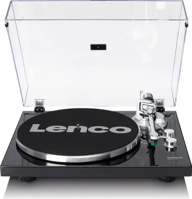 A Lenco LBT-215BK turntable is shown from a slightly elevated front-facing angle against a white background. The turntable has a black glossy base, a black felt mat with the Lenco logo in silver, a silver tonearm, and a clear dust cover that is propped ope