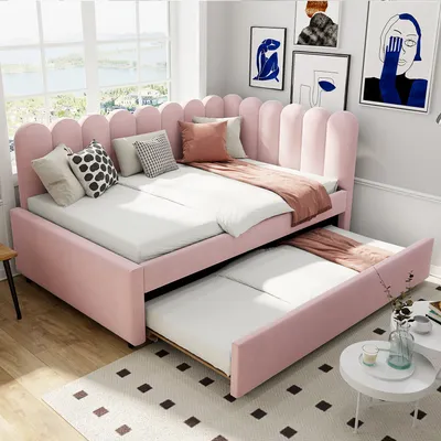 A pink upholstered daybed with a pull-out trundle bed is shown in a bedroom setting.