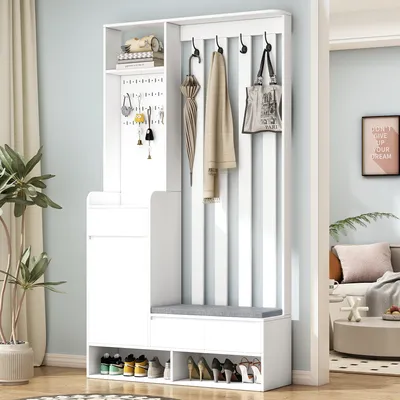 A white entryway storage unit with a bench and hooks, set against a light blue wall.