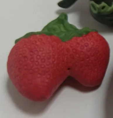 Zwei Erdbeeren die miteinander verbunden sind und grünen Stiel haben. Die Erdbeeren sind detailliert