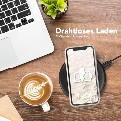 A desk scene with a laptop, coffee, and a smartphone charging wirelessly.