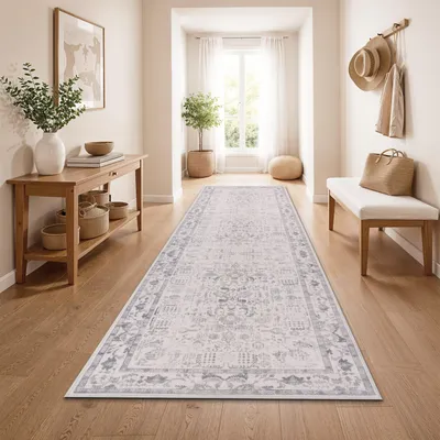 A hallway with a runner rug, console table, and bench.