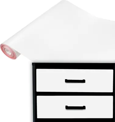 A roll of white vinyl wrap partially unfurled over the top of a black and white two-drawer cabinet.