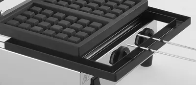 Close-up view of a waffle maker with its top plate open.