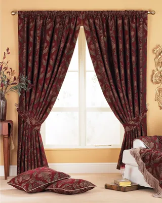 A living room scene with burgundy curtains and pillows.