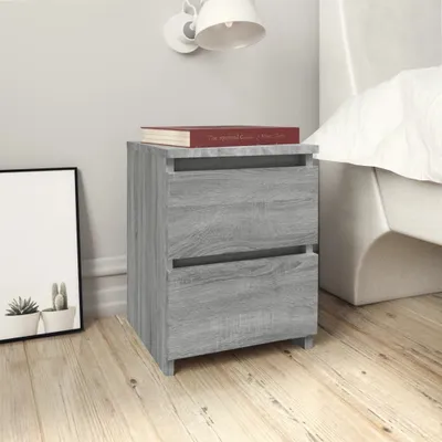 A bedside table with two drawers next to a bed, with a framed picture on the left.