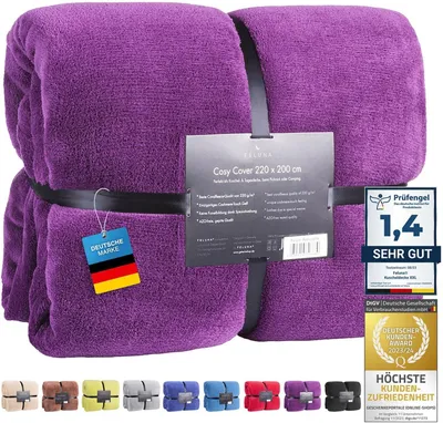 A folded purple blanket with a product tag and marketing labels.