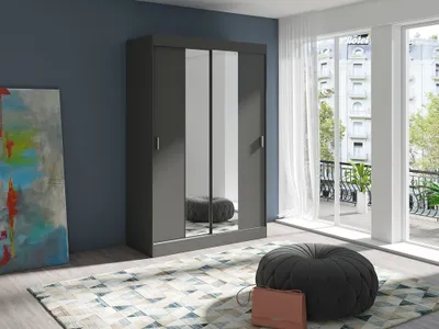 A modern bedroom with a large sliding door wardrobe with mirrored doors, a colorful abstract painting on the wall, and a round ottoman on a patterned rug.