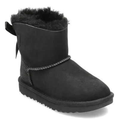 A black UGG boot with a bow on the back is shown against a white background.