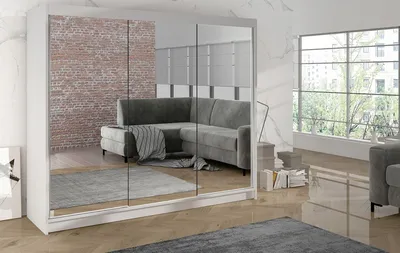 A modern living room with a large mirrored wardrobe reflecting a sectional sofa and a brick wall.