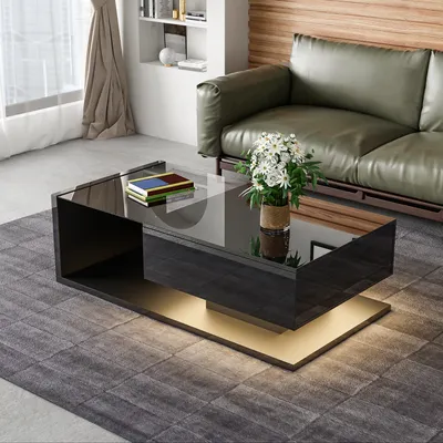 A modern living room scene featuring a coffee table with a glass top, a drawer, and LED lighting, placed on a rug in front of a green leather sofa.