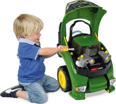 A young boy is playing with a toy John Deere tractor, pretending to fix the engine.