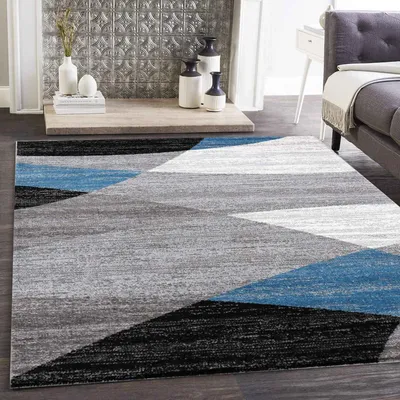 A modern living room with a geometric patterned rug in blue, gray, white, and black.
