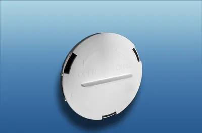 A white circular cap with text and arrows indicating 'OPEN' and 'CLOSE' is shown against a gradient blue and white background.