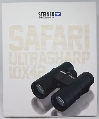 The image shows the packaging of Steiner Safari UltraSharp 10x42 binoculars, with the binoculars themselves placed on the packaging.