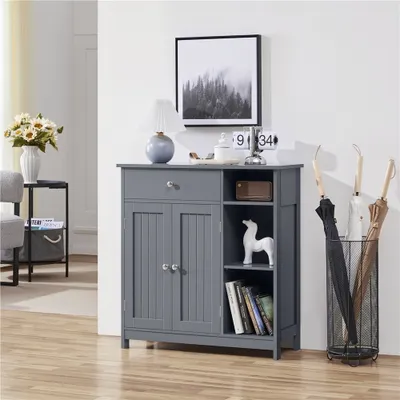A gray cabinet with doors and shelves, decorated with a lamp, a clock, a figurine, and books. An umbrella stand with umbrellas is next to it.