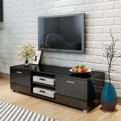 A modern living room with a black high-gloss TV stand against a white brick wall.