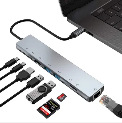 A silver USB hub adapter connected to a laptop, with various cables and memory cards shown around it.