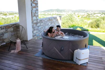 A couple relaxing in a hot tub on a wooden deck with a scenic view.
