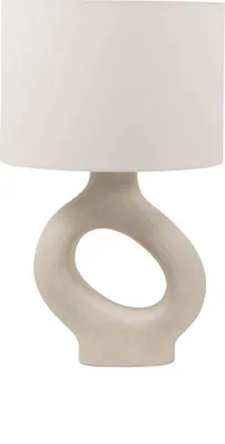 A beige table lamp with an asymmetrical base and a white lampshade, shown against a white background.