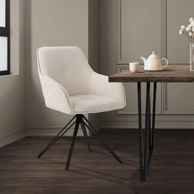 A cream-colored swivel chair with black metal legs is placed next to a dark wood dining table with a teapot and cup on it.