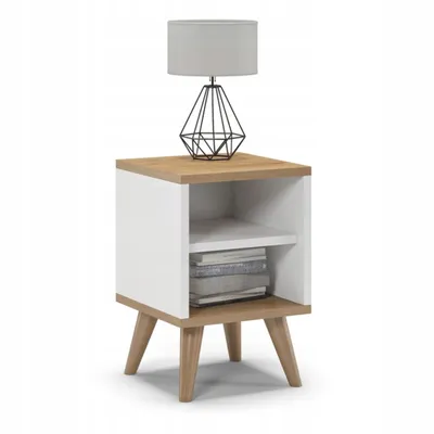 A white and oak bedside table with a lamp on top and books on the shelf.