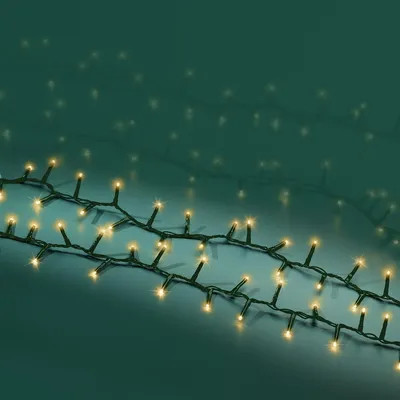 A string of LED lights with a green wire and soft gold lights, laid out in a diagonal pattern against a dark teal background.