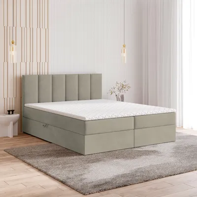 A beige boxspring bed with a mattress and topper is shown in a bedroom setting.