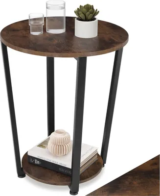 A small round side table with a wood-grain top and black metal legs, decorated with two glasses of water, a small potted plant, and two books with a decorative object on top.