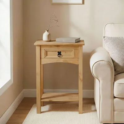A wooden console table with a drawer and a shelf, placed next to a cream-colored sofa in a room with light beige walls and a window.