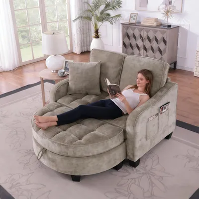 A woman is relaxing on a chaise lounge sofa while reading a book. The sofa is in a living room setting with a window and a cabinet in the background.