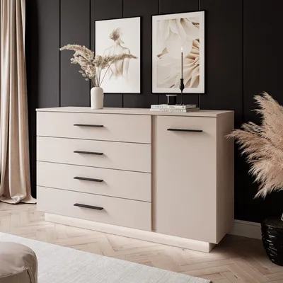 A modern dresser with black handles and LED lighting, styled in a room with artwork and dried plants.