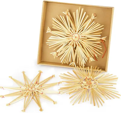 Three straw star ornaments are displayed on a white background, with one larger ornament inside a cardboard box.