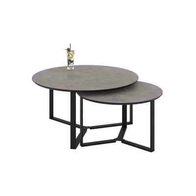 A set of two nesting coffee tables with round tops and black metal legs, with a drink on the larger table.