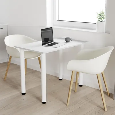 A white table with two chairs, a laptop, and a cup of coffee, set up in a bright room with a window.