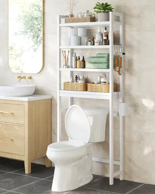 A bathroom scene featuring a white toilet with an over-the-toilet shelving unit filled with bathroom essentials, next to a wooden vanity with a sink and a mirror.