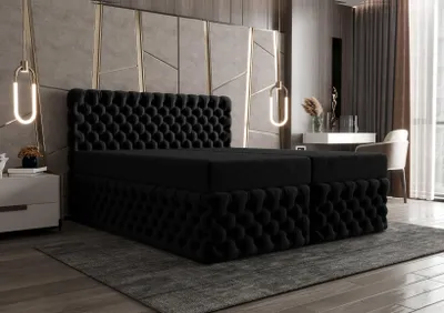 A luxurious bedroom setting with a large black tufted boxspring bed as the focal point.
