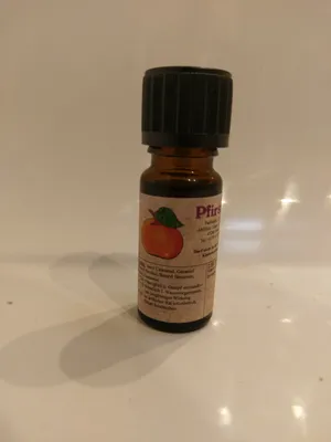 Kleine braune Flasche mit einem schwarzen Verschluss. Auf dem Etikett steht "Pfirsich".