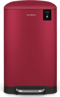 A red pedal trash can with a black base and a small black label on the top right.