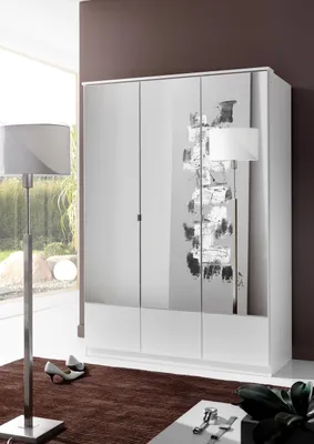 A white wardrobe with a decorative abstract design on one of its doors, placed in a room with a brown rug and a floor lamp.