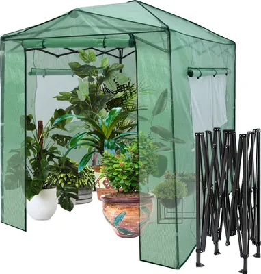 A green greenhouse filled with various potted plants, with a folded metal frame to the right.