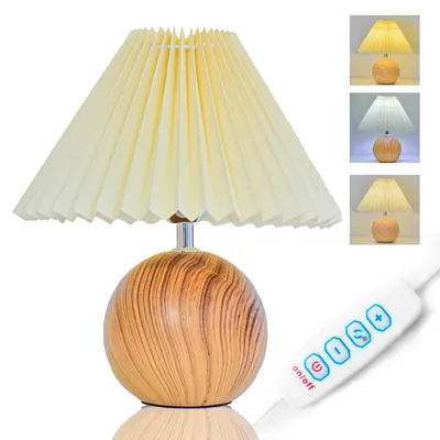 A table lamp with a pleated fabric shade and a wood-grain patterned spherical base, shown with a remote control and inset images demonstrating different light colors.