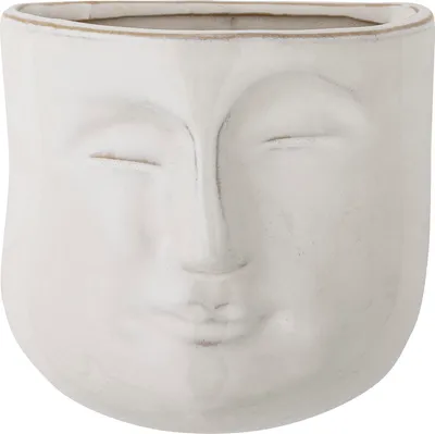 A white ceramic planter shaped like a face with closed eyes.