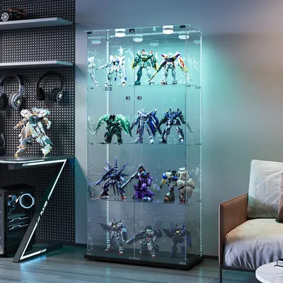 A display cabinet filled with robot figurines, placed in a room with a couch and a desk with computer equipment.